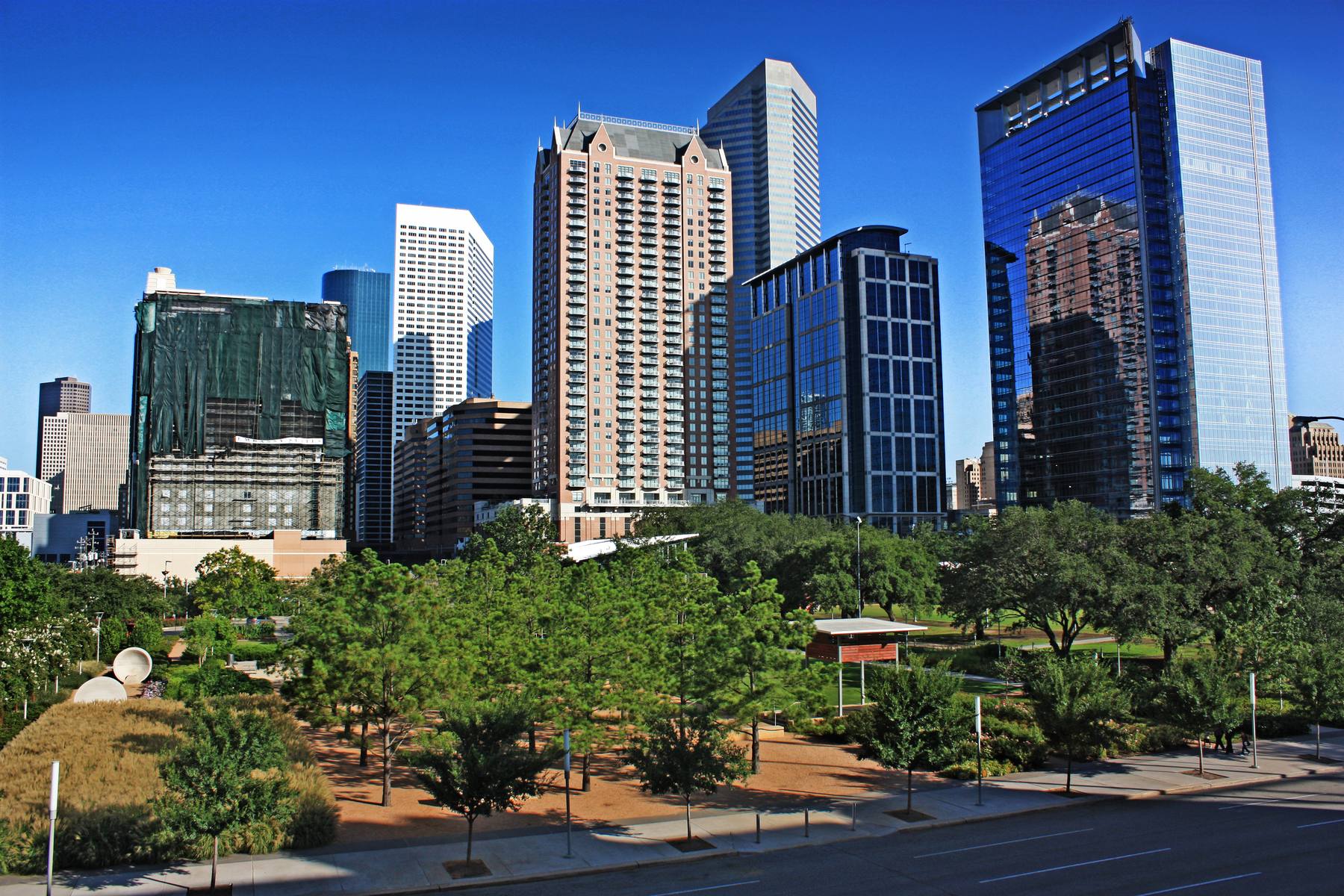 The downtown Houston skyline rising over the trees and lawns of Discovery Green, the twelve-acre park across from the convention center and a short walk from Daikin Park