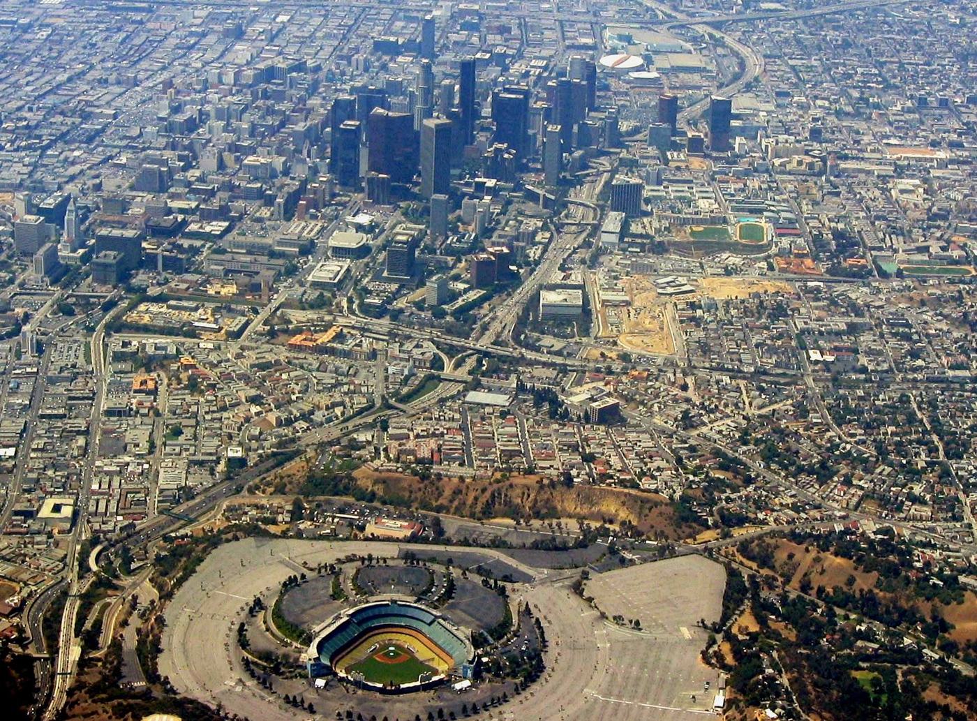 An aerial view of Dodger Stadium in the hills above Los Angeles, with the downtown skyline in the distance