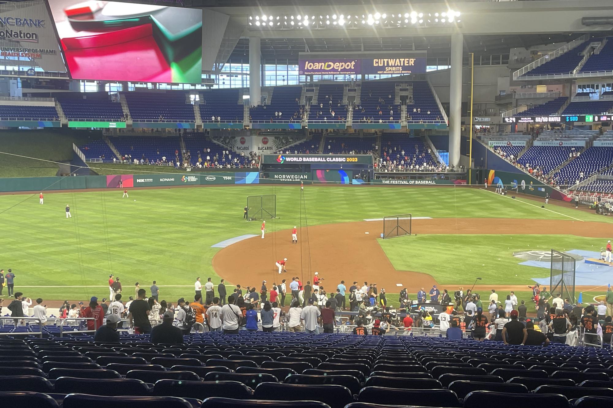 Batting practice at loanDepot park under the closed roof before the 2023 World Baseball Classic final, a loanDepot sign above the outfield and a World Baseball Classic banner on the wall, the seating bowl still mostly empty