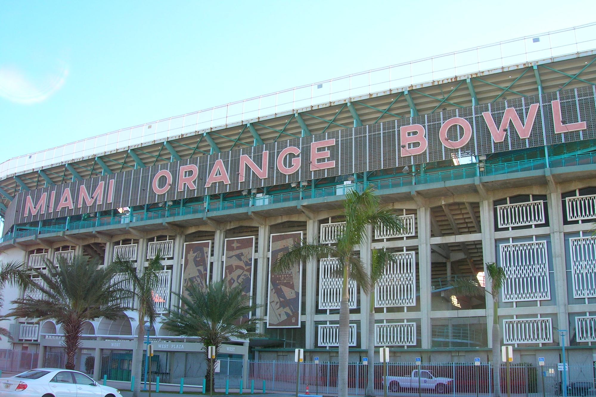 The Miami Orange Bowl, its name spelled out in tall coral letters across the upper facade above palm trees and the concrete grille of the West Plaza entrance