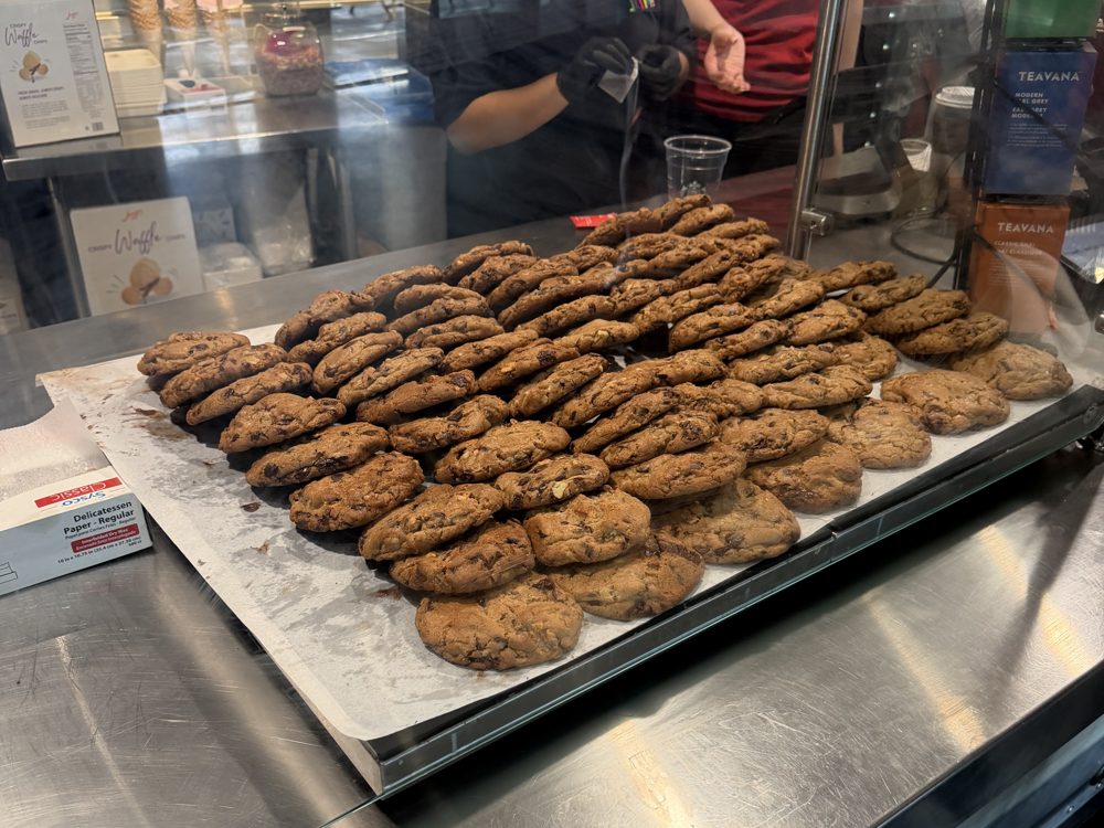 A full tray of large chocolate chip walnut cookies behind the counter glass at an espresso stand on the 200 level of T-Mobile Park