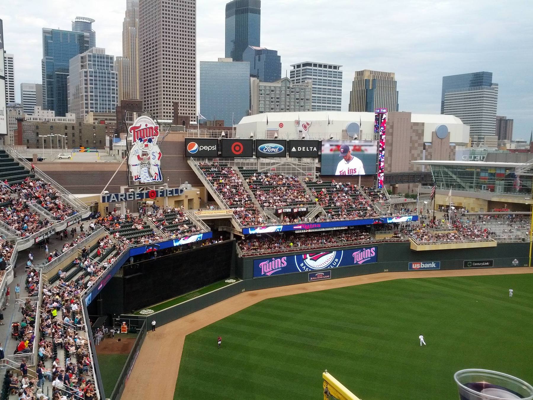 The downtown Minneapolis skyline beyond the outfield at Target Field, with the open-air seating bowl in front of it