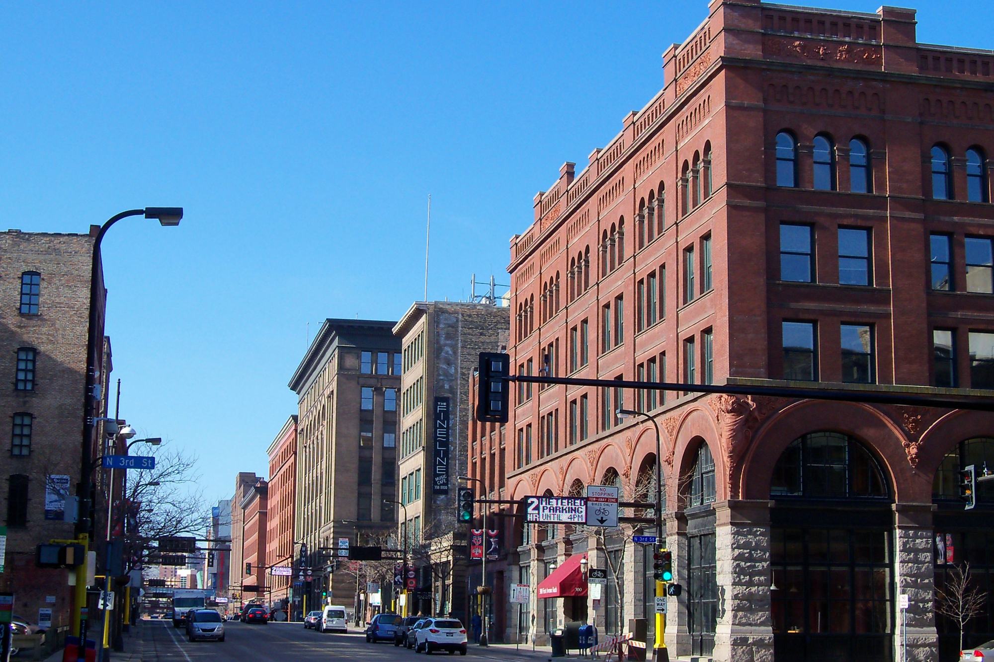 A brick warehouse block in the Minneapolis Warehouse District near Target Field, storefronts along the street under a clear sky